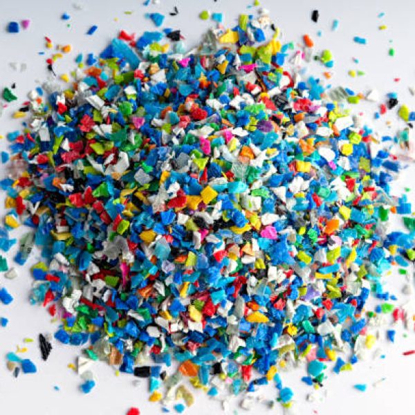 Small pieces of crushed plastic. Crushed bottle caps for recycling. Plastic waste that will be mixed with plastic vergin. Concept reducing plastic.