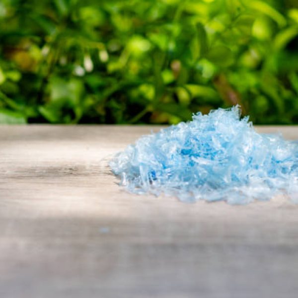 A Pile of PET bottle flakes with green tree blur background